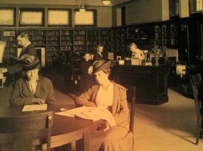 Black and white historical photo of two women at a table reading