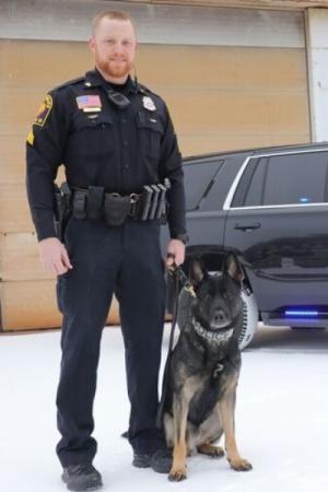 Police officer standing next to a dog.